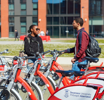 Two cyclists chatting at a Santander Cycles docking station 